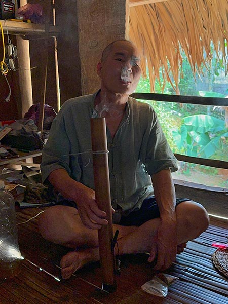 El hombre de la casa fumando la pipa de agua tradicional hecha con un tubo de bambú